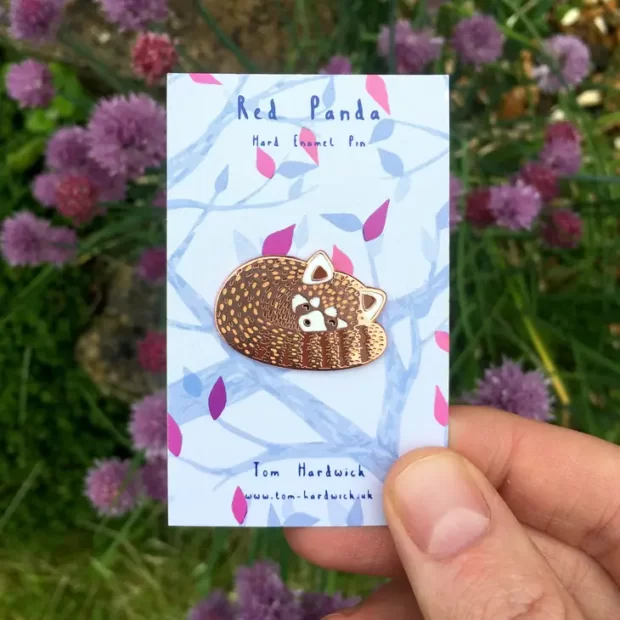 Red panda enamel pin with a beautifully patterned backing card. Artists name and animal name are shown.